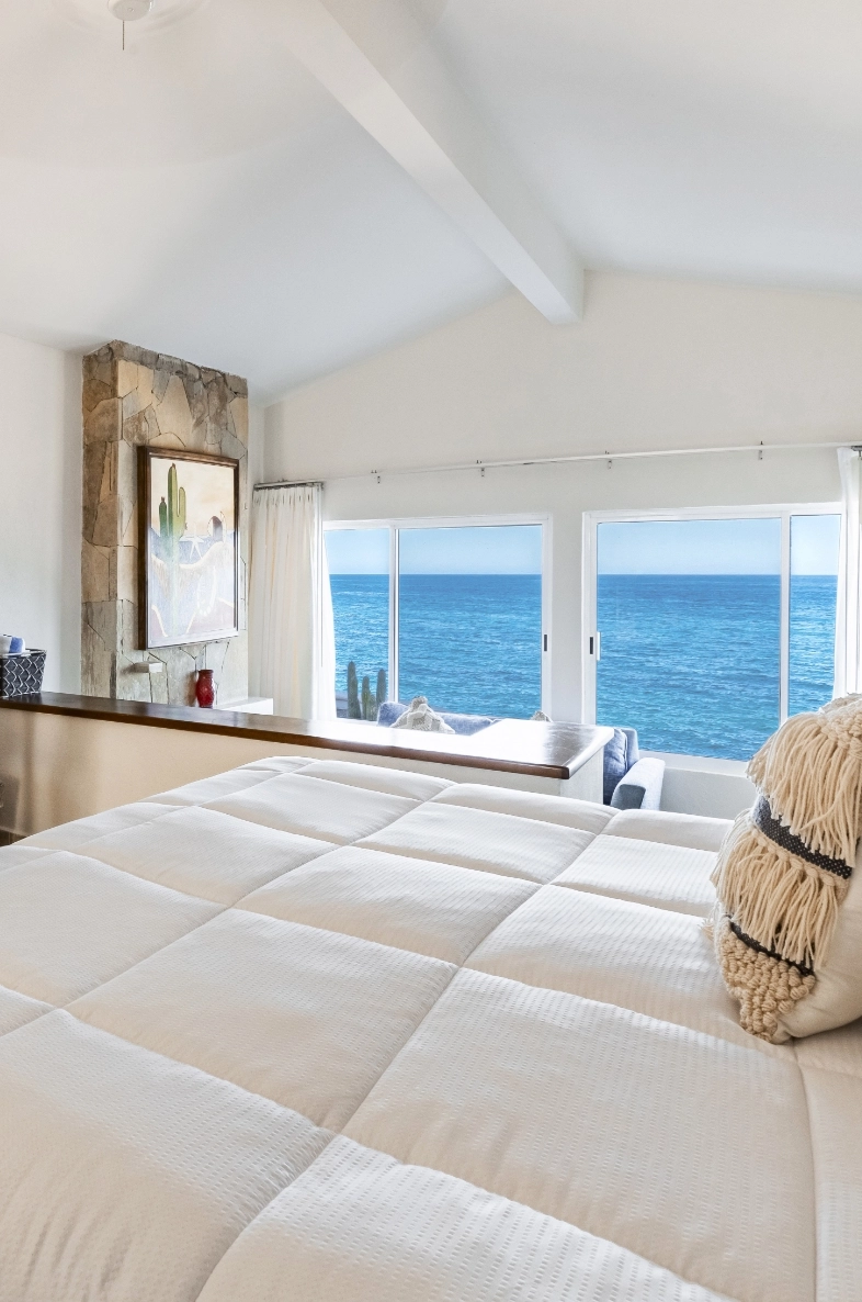 a bedroom with a large bed and a large window overlooking the ocean